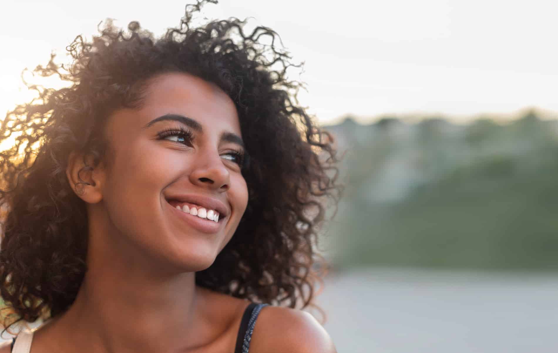 Outdoor portrait of smiling african american girl Woman excited about general dental care at Renovo Prosthodontics